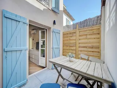 a patio with a wooden table and blue doors at Lovely renovated apart Terrace - Mobility lease in Cannes