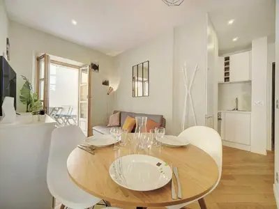 a dining room with a wooden table and white chairs at Lovely renovated apart Terrace - Mobility lease in Cannes
