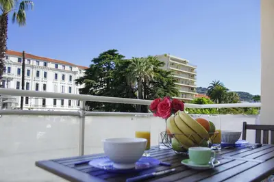 a table with a bowl of bananas and a vase of flowers at Beau 2 pièces au centre de Cannes - Parking in Cannes