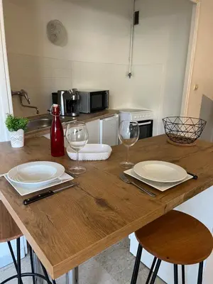 a wooden table with two plates and wine glasses at Coquet studio 10 min de Cannes in Le Cannet