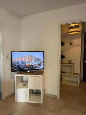 a flat screen tv sitting on a stand in a living room at Coquet studio 10 min de Cannes in Le Cannet