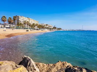 a view of a beach with palm trees and buildings at Studio Design et Cosy à 8 min à Pied des Plages in Cannes