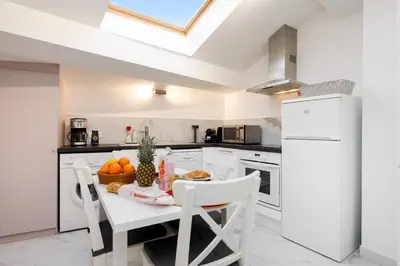 a white kitchen with a table with fruit on it at Le Napoléon, 1min Palais des Festivals in Cannes