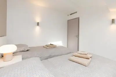 two beds in a white room with towels on them at Le Napoléon, 1min Palais des Festivals in Cannes