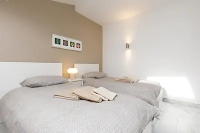 two beds in a white room with towels on them at Le Napoléon, 1min Palais des Festivals in Cannes