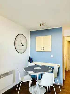 a dining room with a table and chairs and a clock at Superbe appartement in Cannes