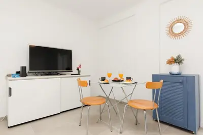 a kitchen with a table and two chairs and a tv at Le Lido YourHostHelper in Cannes