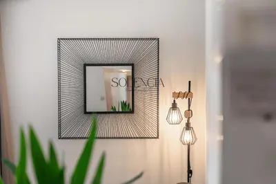 a mirror on a wall next to two lights at 2 pièces rue d'Antibes - Climatisation in Cannes