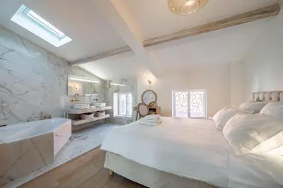 a white bedroom with a large bed and a bath tub at 4 pièces sur la rue d'Antibes - Rénové et climatisé in Cannes