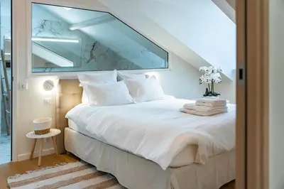 a bedroom with a white bed with a large window at 4 pièces sur la rue d'Antibes - Rénové et climatisé in Cannes