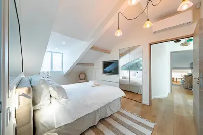 a bedroom with a large white bed and a mirror at 4 pièces sur la rue d'Antibes - Rénové et climatisé in Cannes