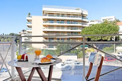 a table with a plate of food on a balcony at Colline Azur YourHostHelper in Cannes