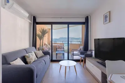 a living room with a couch and a flat screen tv at L'AZUR avec terrasse vue mer, piscine accessible et près des plages in Cannes