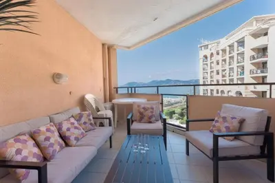 a balcony with a couch and chairs and a table at L'AZUR avec terrasse vue mer, piscine accessible et près des plages in Cannes