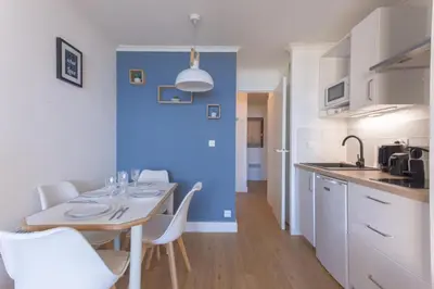 a kitchen with a table and chairs and a blue wall at L'AZUR avec terrasse vue mer, piscine accessible et près des plages in Cannes