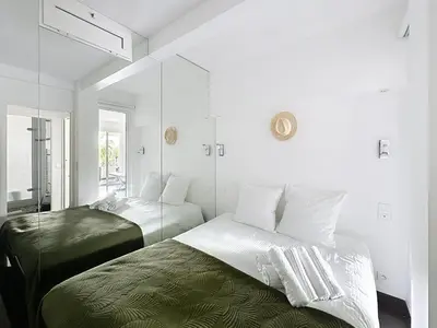 a white bedroom with two beds and a mirror at One bedroom apartment on La Croisette - Sea view in Cannes