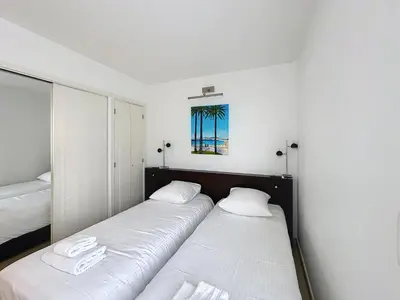 two beds in a room with white walls at Modern 2-Bedroom Stunning Sea View on La Croisette in Cannes