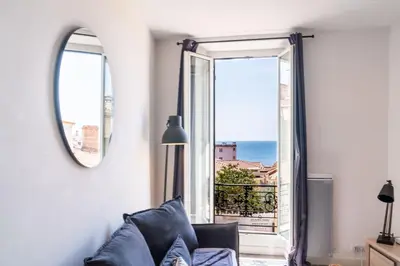 a living room with a couch and a large window at Le refuge du Suquet, quartier authentique de Cannes, vue mer in Cannes