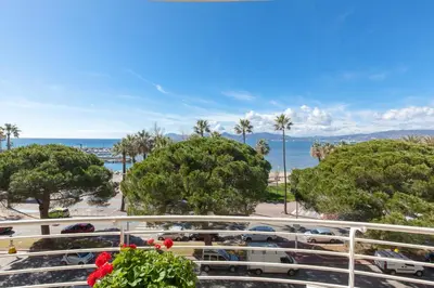 a view of a parking lot with palm trees and the ocean at Sea View 95m Apartment with Large Terrace Cannes Croisette in Cannes