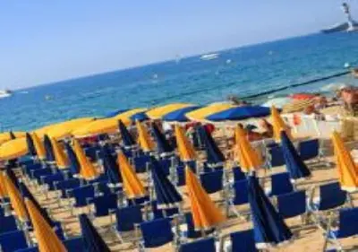 a group of chairs and umbrellas on a beach at En ville un coin de campagne in Le Cannet