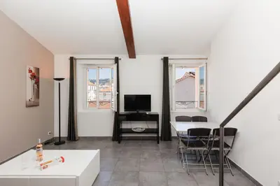 a living room with a table and chairs and a tv at Residence Aout 41 in Cannes