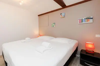 a bedroom with a large white bed and a lamp at Residence Aout 41 in Cannes