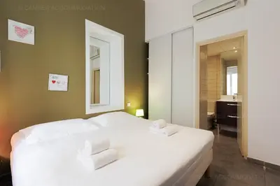a bedroom with a white bed with two towels at Residence Aout 43 in Cannes