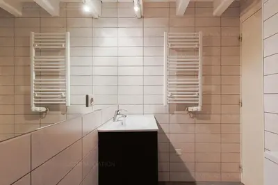 a white tiled bathroom with a sink and mirrors at Residence Aout 42 in Cannes