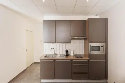 a kitchen with brown cabinets and a microwave at Residence Aout 32 in Cannes
