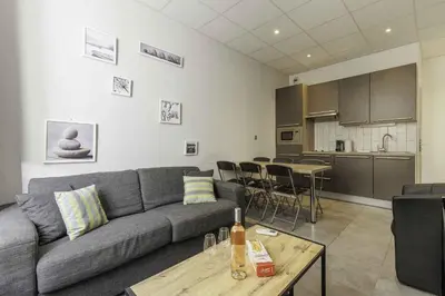 a living room with a couch and a table and a kitchen at Residence Aout 11 in Cannes
