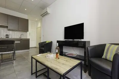 a living room with a couch and a table with a television at Residence Aout 11 in Cannes