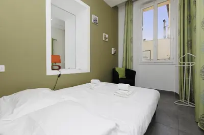 a white bed in a room with a window at Residence Aout 11 in Cannes