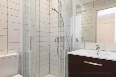 a white bathroom with a shower and a sink at Residence Aout 31 in Cannes