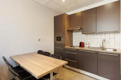 a kitchen with a wooden table and some chairs at Residence Aout 31 in Cannes
