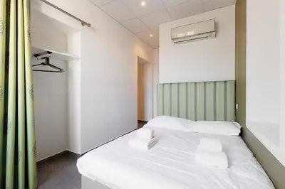 a bedroom with a white bed with a green curtain at Residence Aout 31 in Cannes