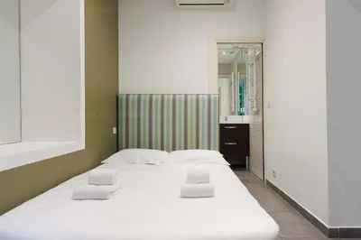 a bedroom with a large white bed with towels on it at Residence Aout 12 in Cannes