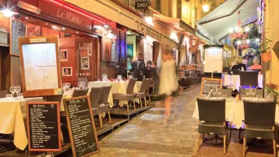 a woman in a white dress walking through a restaurant at Residence Aout 22 in Cannes