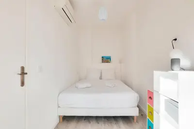 a small bedroom with a bed in a white room at Le Petit Fleury – Balcony, Calm in Cannes in Cannes
