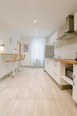 a kitchen with white cabinets and a table and chairs at La Perle du Suquet, zone piétonne in Cannes
