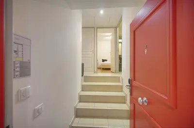 a hallway with a red door and stairs at Immogroom - T2 - AC - Suquet in Cannes
