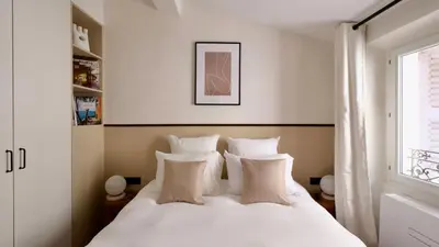 a bedroom with a white bed with pillows and a window at Exceptional facing Palais Cannes 3 in Cannes