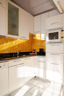 a white kitchen with a sink and a microwave at Sunny duplex close to Croisette, free parking in Cannes