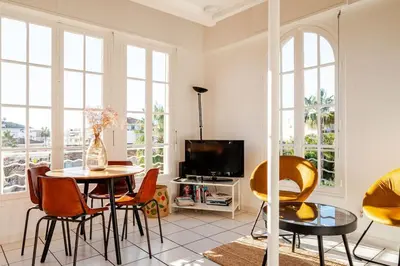 a living room with a table and chairs and a tv at Sunny duplex close to Croisette, free parking in Cannes