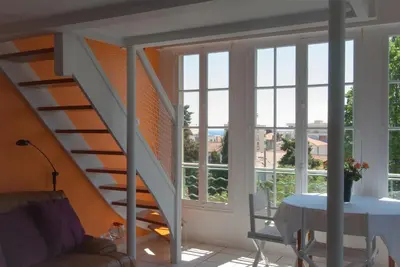 a living room with a staircase and a table with a couch at Sunny duplex close to Croisette, free parking in Cannes