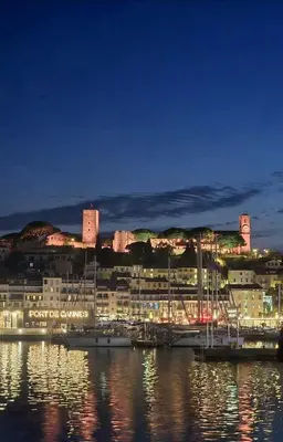 a city with a marina at night with a castle at HomeForville in Cannes