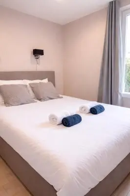 a white bed with two blue pillows on it at Serenity in Cannes