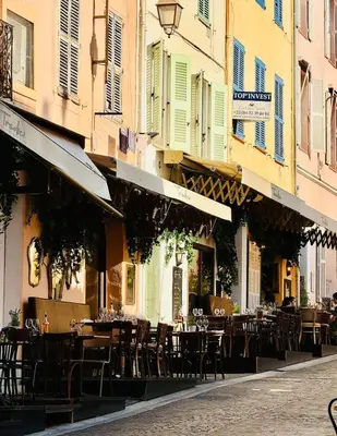 an outdoor cafe with tables and chairs in a street at Tredici By SCLS Locations in Cannes