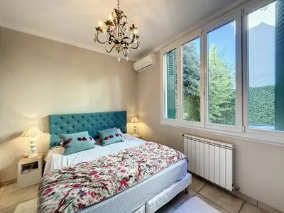 a bedroom with a bed with a blue headboard and windows at 3-Bedroom house with terrace 5 minutes walking from La Croisette in Cannes