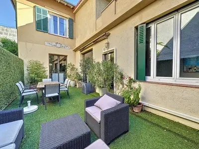 a patio with wicker chairs and a table and a building at 3-Bedroom house with terrace 5 minutes walking from La Croisette in Cannes