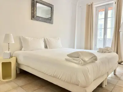 a bedroom with a white bed with a mirror on the wall at Cannes 2 Bedroom Apartment - 19JDR2 in Cannes